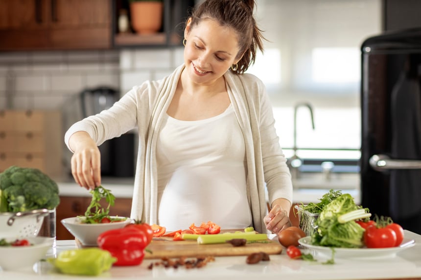Femme enceinte souriante se préparant un repas équilibré et coloré